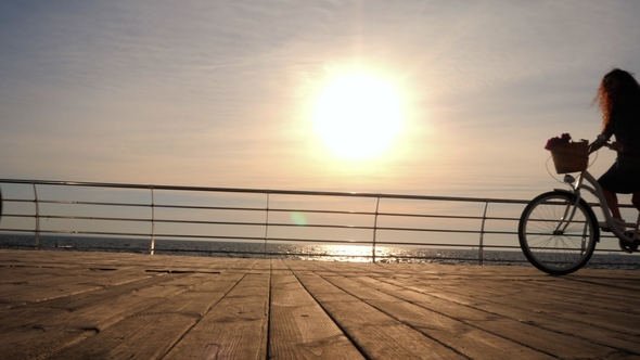 Silhouettes of Young Couple Riding Bicycles on Sea Embankment and Having Fun Together. Girl and Boy alt
