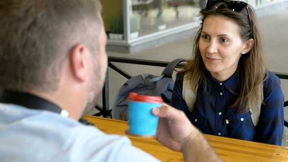 Young Man Takes a Glass of Coffee From His Lover and Drinks From It. The Girl Is Surprised at the