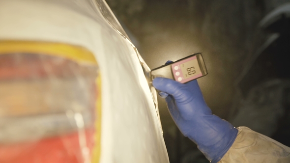 View of Measuring a Thickness of Primer on a Car Surface Using a Thickness Gauge alt