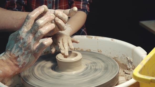 Teacher Teaching the Child to Form Clay on a Potter's Wheel