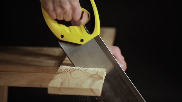 Man Sawing Wooden Board with Hand Saw