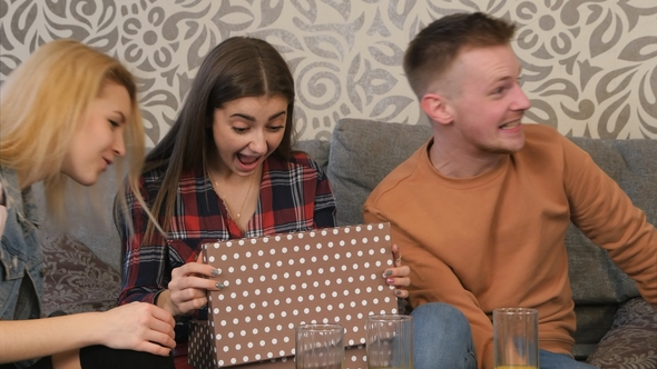 Beautiful Young Girl Opens a Gift Box and Is Surprised and Happy with What She Sees alt