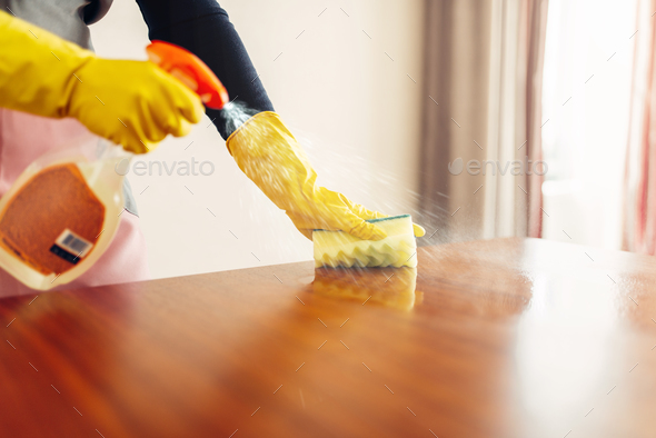 Housemaid hands cleans table with cleaning spray - Stock Photo - Images