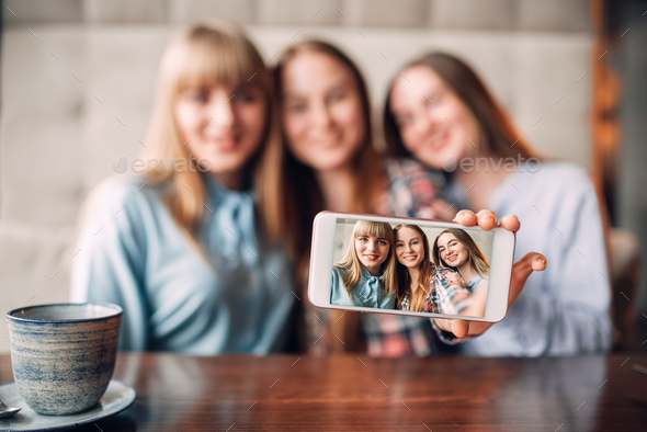 Three girlfriends makes selfie on camera in cafe - Stock Photo - Images