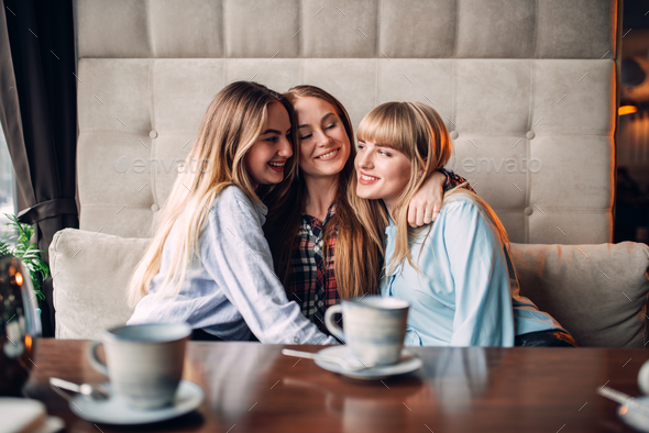 Three attractive girlfriends hugs together in cafe Stock Photo by NomadSoul1