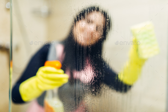 Maid in gloves cleans glass with a cleaning spray - Stock Photo - Images