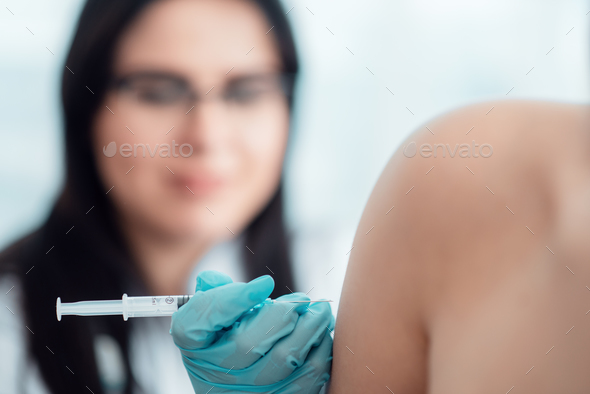 Family doctor gives a syringe injection in hand - Stock Photo - Images