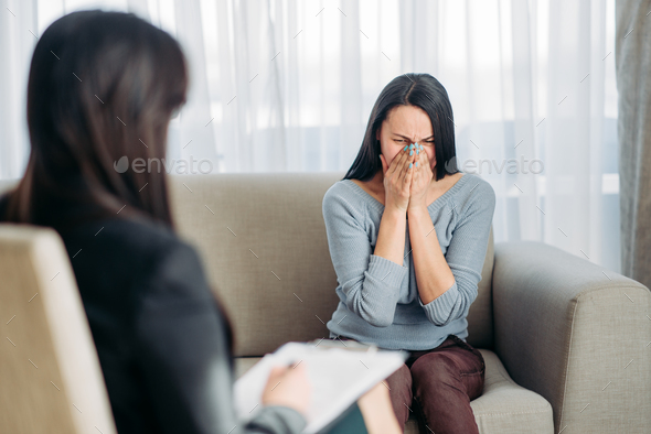 Female patient sitting on sofa at psychotherapist - Stock Photo - Images
