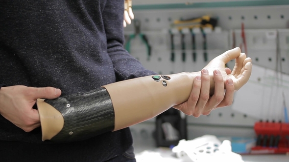 of Male Engineer Holding Bionic Hand with Opening Ang Closing Fingers. alt