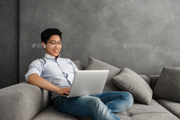 Happy young asian man using laptop - Stock Photo - Images