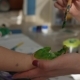 Woman Paints with Brush on Baby Hand for Making Green Handprints.  Shot - VideoHive Item for Sale