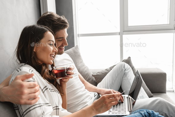 Married couple man and woman sitting on sofa in apartment near b - Stock Photo - Images