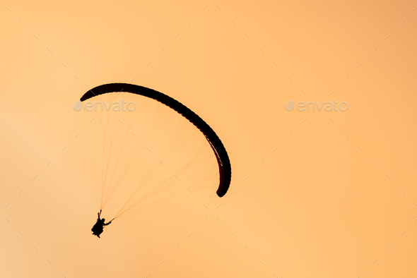 Silhouette of paraglider tandem flying in orange sky - Stock Photo - Images