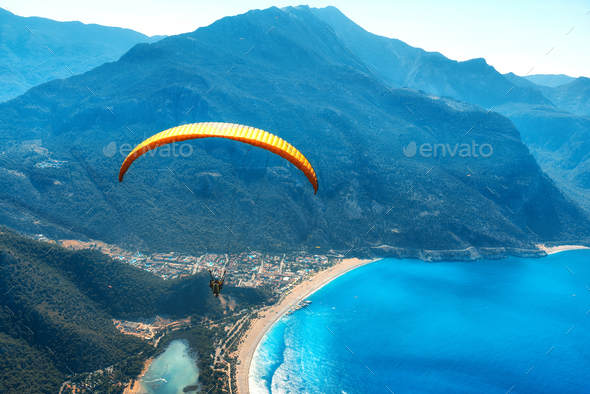Paraglider tandem flying over the sea with blue water and mountains - Stock Photo - Images