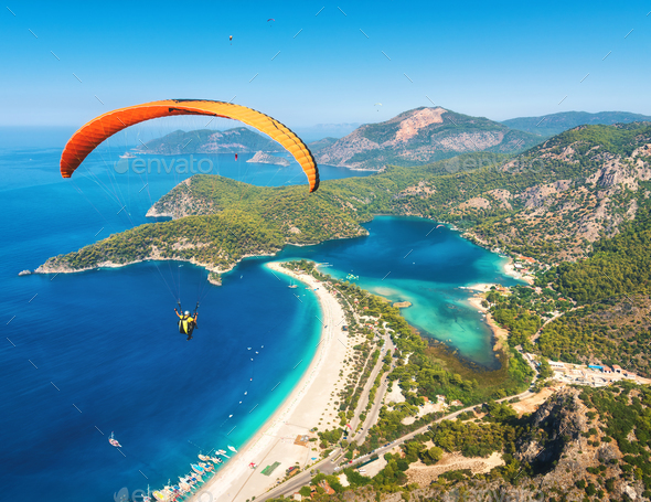 Paraglider tandem flying over the sea with blue water and mountains - Stock Photo - Images