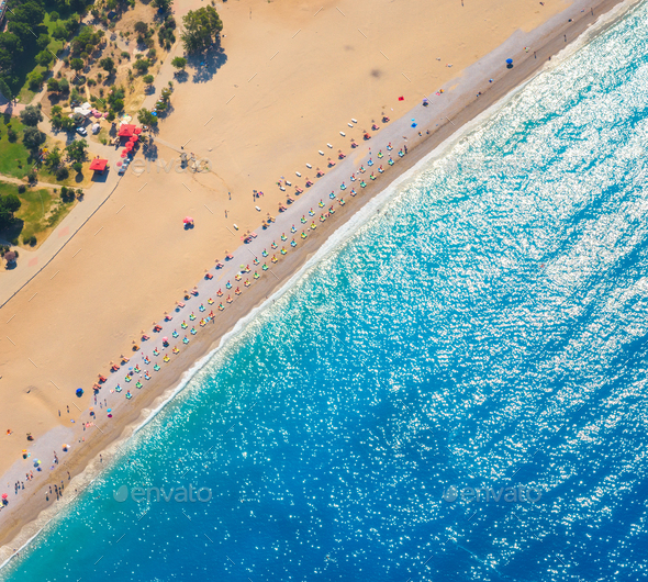 Aerial view of sandy beach with colorful chaise-lounges and blue sea - Stock Photo - Images