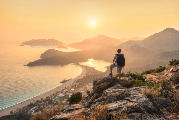 Young sporty man with backpack, seashore and mountains - Stock Photo - Images
