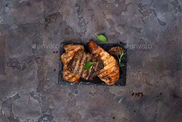 Fresh three types of grilled steak (chicken, pork, beef) on slate plate with herbs - Stock Photo - Images