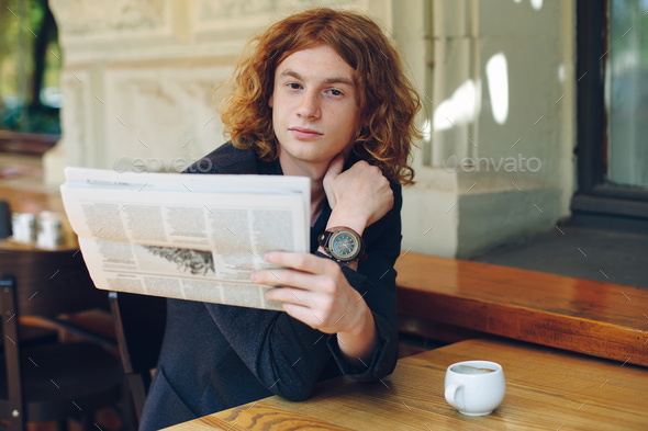 Young man reading a newspaper in the morning - Stock Photo - Images