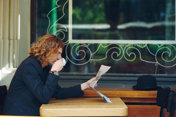Hipster man drinking coffee while reading - Stock Photo - Images