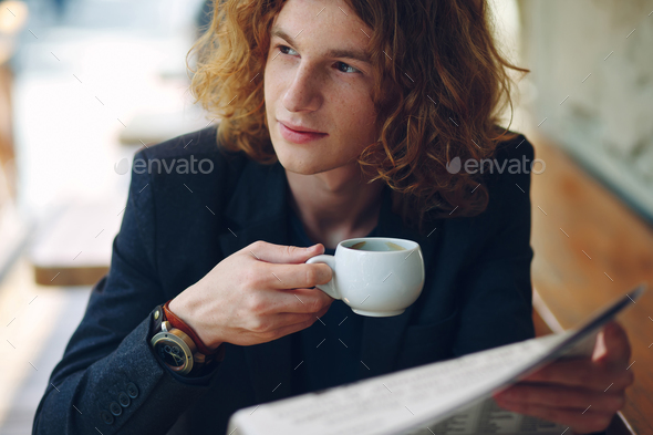 Reddish young entrepreneur drinking coffee while reading - Stock Photo - Images