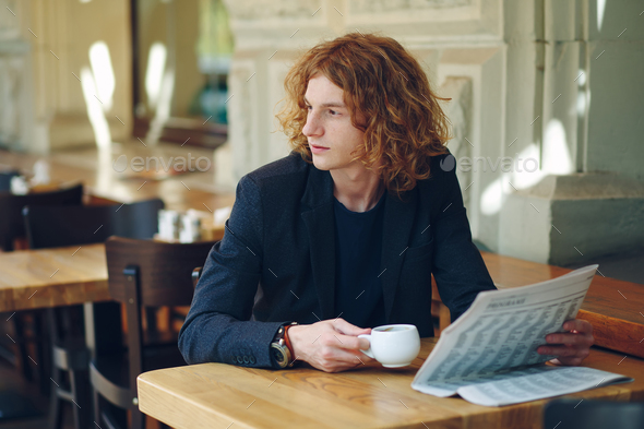 Hipster man drinking coffee while reading - Stock Photo - Images