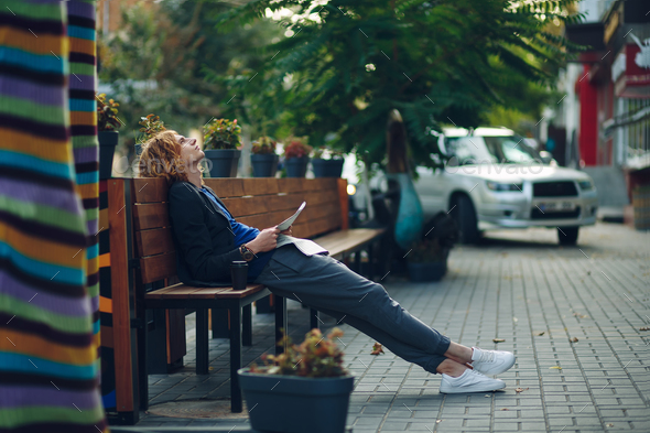 Man dreaming while lying on a long wooden bench - Stock Photo - Images