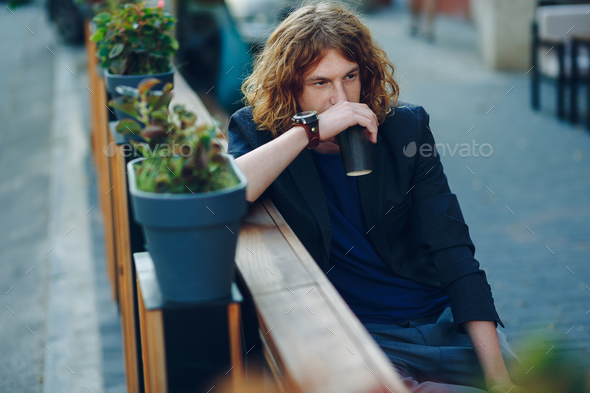 Man resting on a bench with a coffee to go - Stock Photo - Images