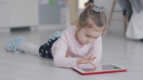 Relaxing Girl Playing Tablet on Floor alt
