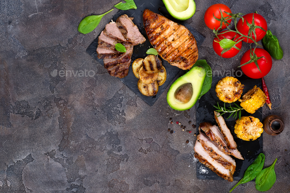 Fresh three types of grilled steak on slate plate with herbs, tomato, avocado and grilled potatoes - Stock Photo - Images