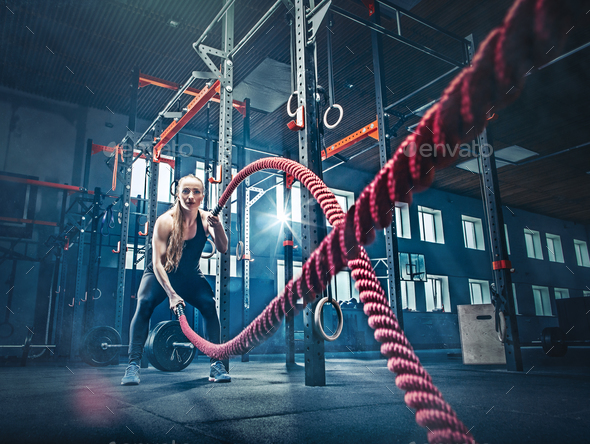 Woman with battle rope battle ropes exercise in the fitness gym. Stock Photo by master1305