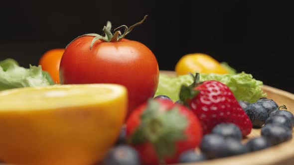 Variety of Color Fruits and Berries and Vegetables with Greens are Rotating on the Plate alt