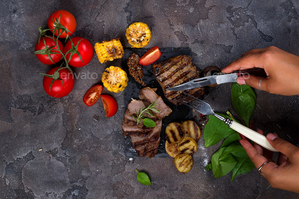 Female hands with a fork and knife cut Beef steak - Stock Photo - Images
