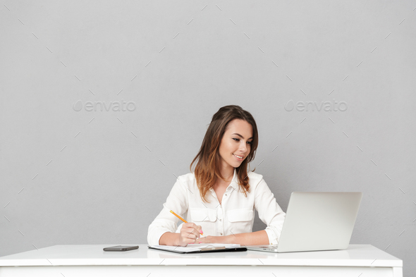 Amazing cheerful young business woman using laptop computer writing notes. - Stock Photo - Images