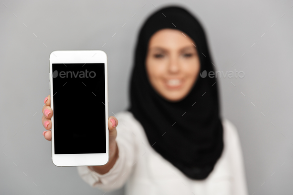 Blurry image of smiling muslim woman 20s in islamic headscarf wi - Stock Photo - Images