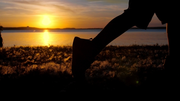 The Legs of a Boy Running in the Setting Sun. Silhouette, Picking Up Dust and Fluff