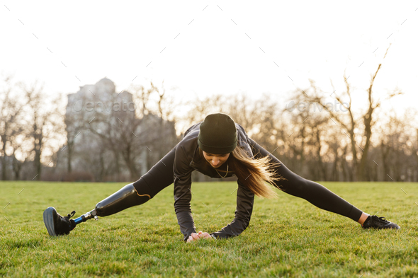 Photo of handicapped sportswoman in black tracksuit, stretching Stock Photo by vadymvdrobot