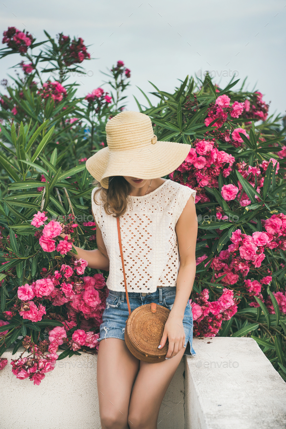 Young blonde woman sitting near blooming oleander tree - Stock Photo - Images