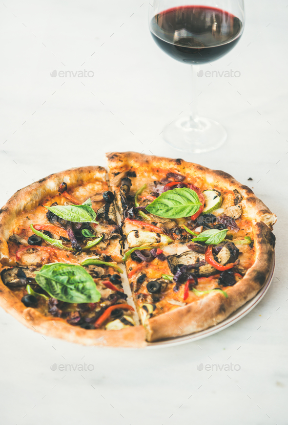 Freshly baked pizza with vegetables, basil and glass of wine - Stock Photo - Images