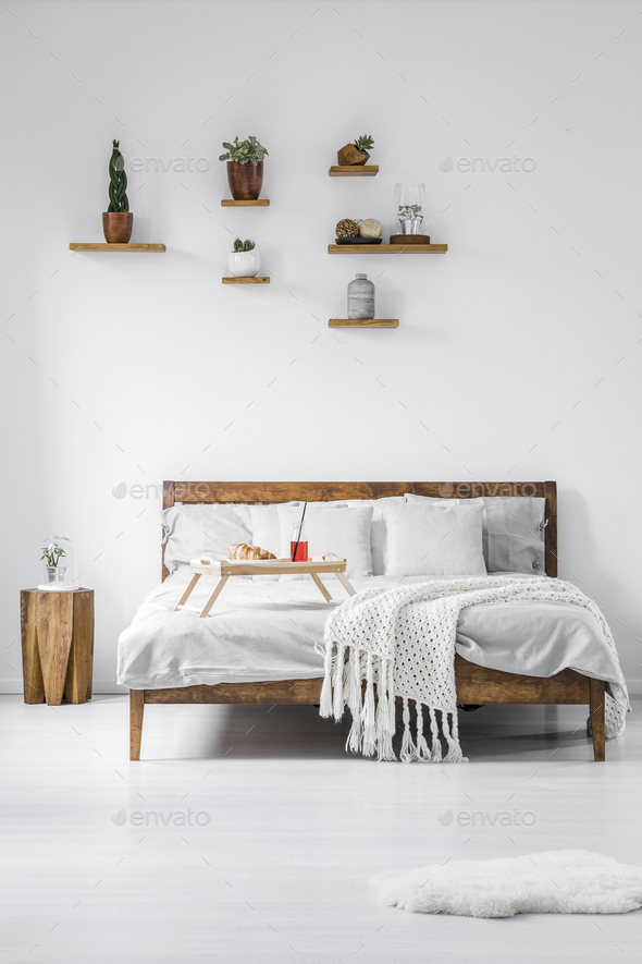 Front view of a wooden framed double bed with linen, pillows and - Stock Photo - Images
