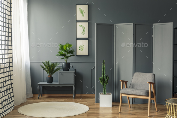 A chair standing in front of a decorative, grey screen next to a - Stock Photo - Images