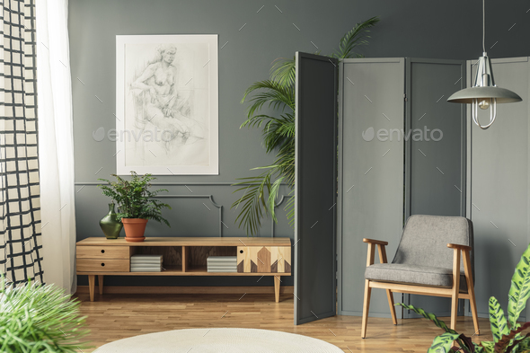 Retro armchair against a gray screen next to a drawing hanging o - Stock Photo - Images