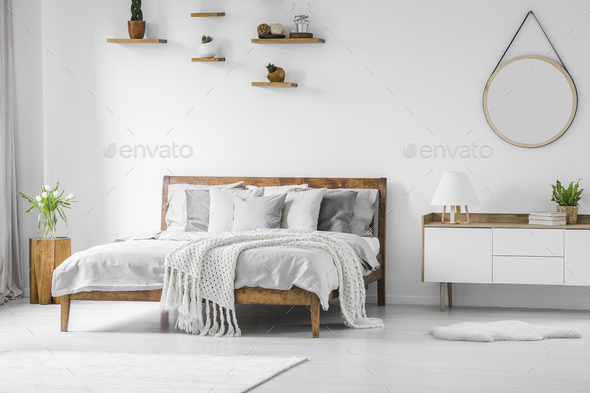 Comfortable big wooden framed bed with linen, pillows and blanke - Stock Photo - Images