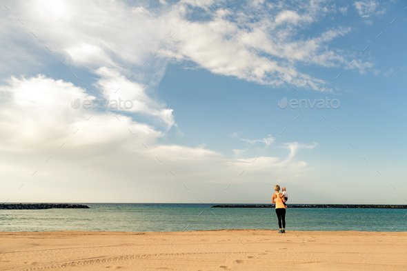 Mother with baby boy enjoying sunrise on a beach - Stock Photo - Images