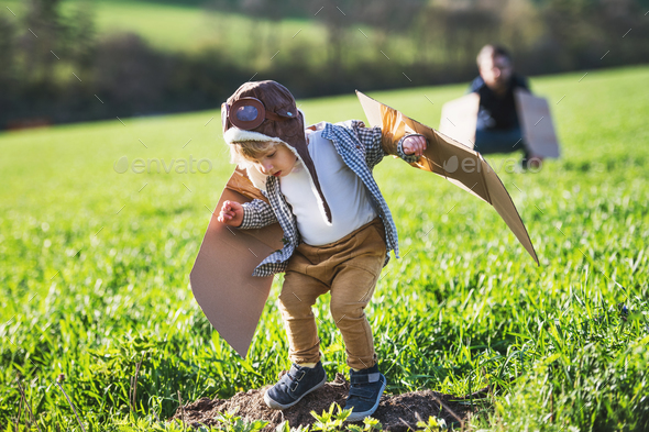 Happy toddler boy and father playing with wings outside in spring nature. - Stock Photo - Images