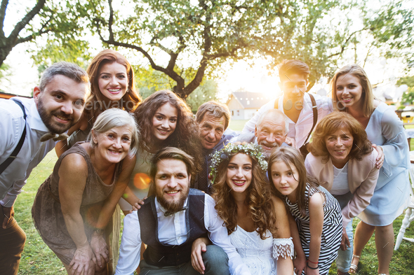 Bride, groom, guests posing for the photo at wedding reception outside ...