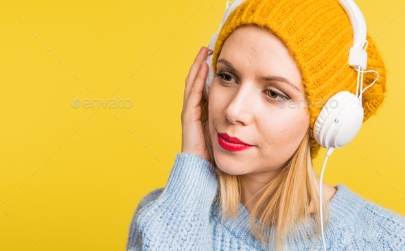 Portrait of a young beautiful woman with headphones in studio on a yellow background. - Stock Photo - Images