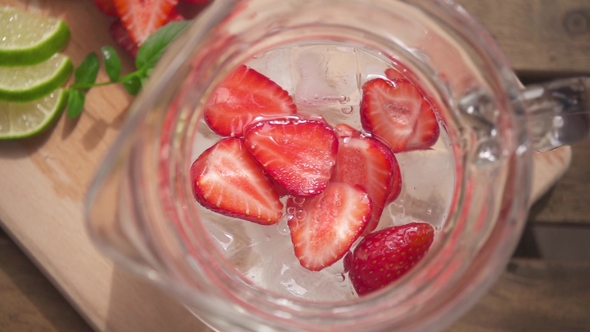 Halves of Strawberries in a Decanter with Ice and Water Top View