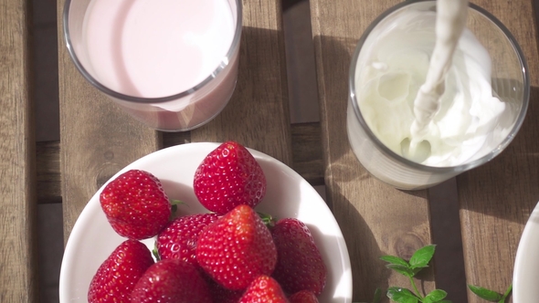 Two Glasses with Milkshakes and a Glass with Flowing Milk