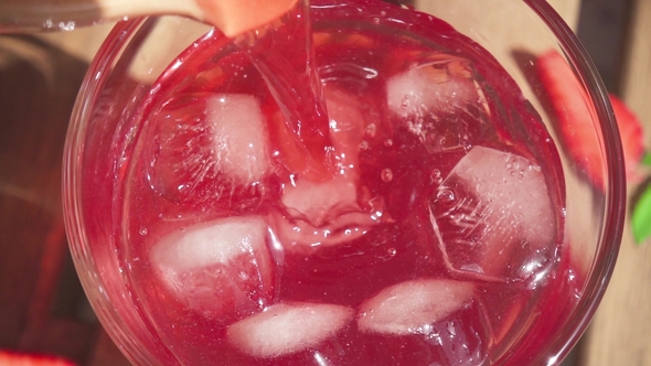 Juice Is Poured From a Jug Into a Glass with Ice